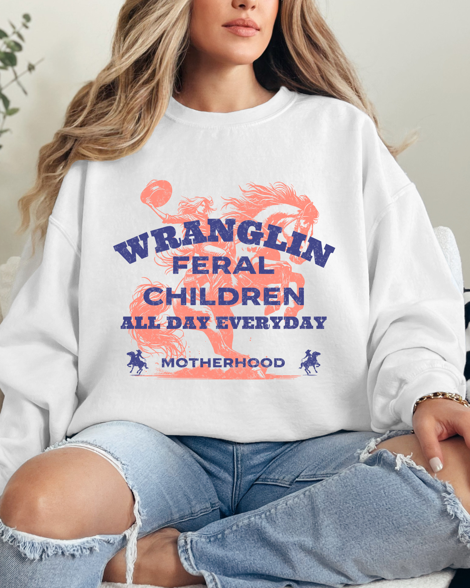 Person wearing a white sweatshirt with text and graphics, sitting on a couch.