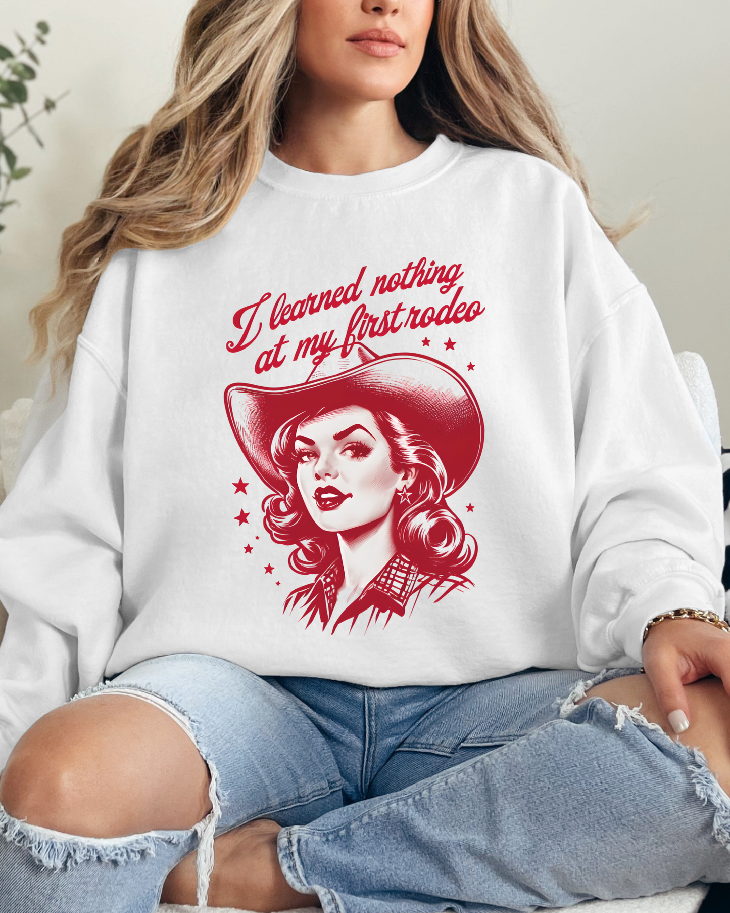 Person wearing a white sweatshirt with a graphic design and text, sitting on a couch.