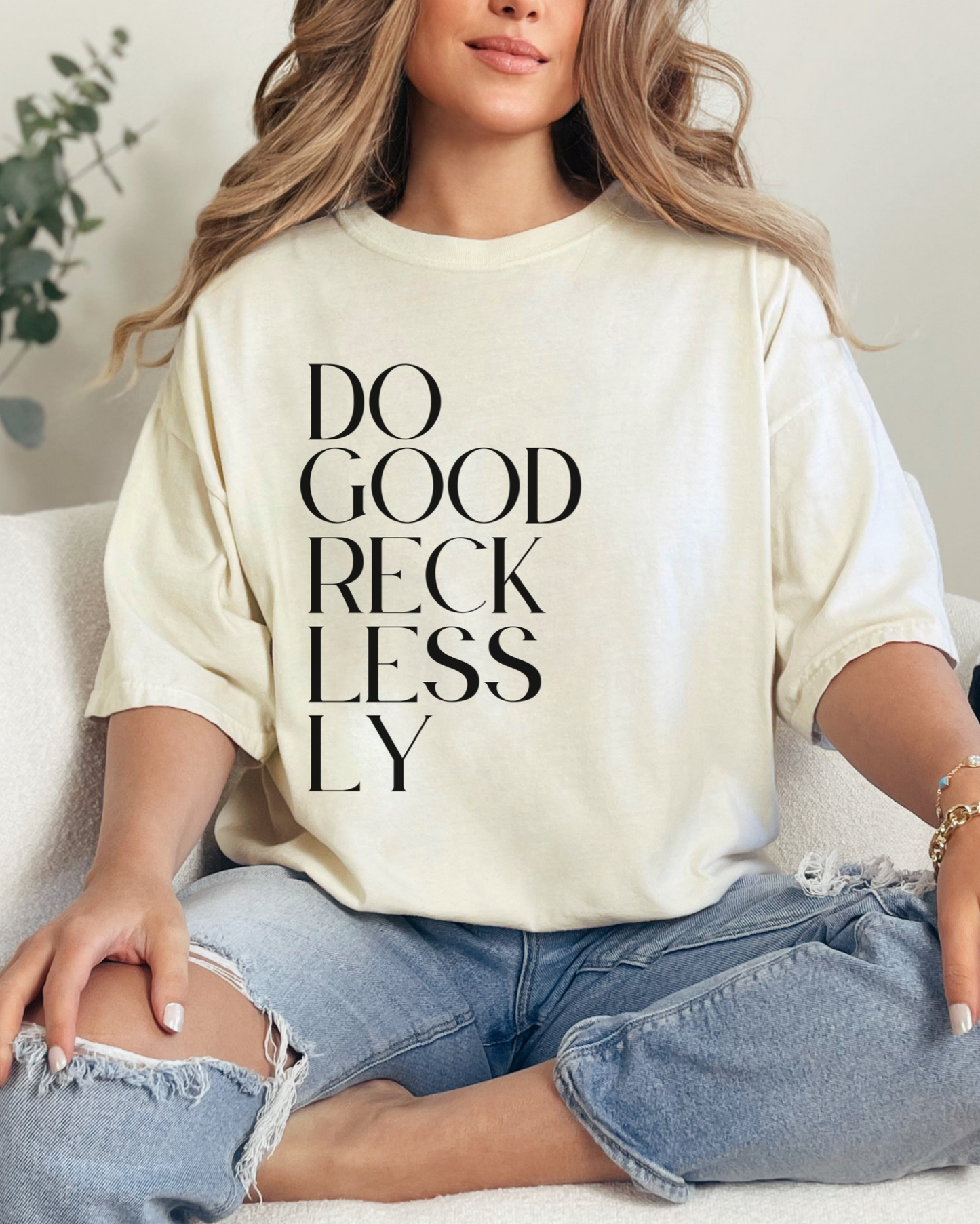 Person wearing a white sweatshirt with text, sitting on a couch.
