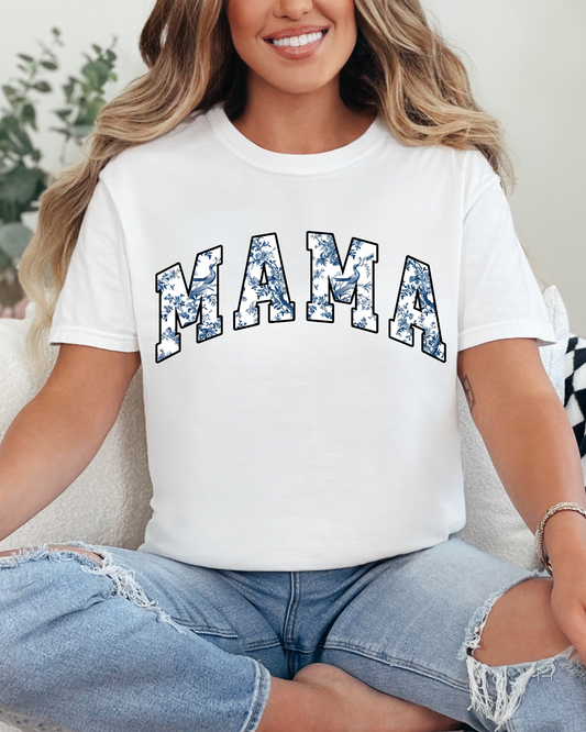 Woman wearing a white t-shirt with 'MAMA' printed on it, sitting on a couch.