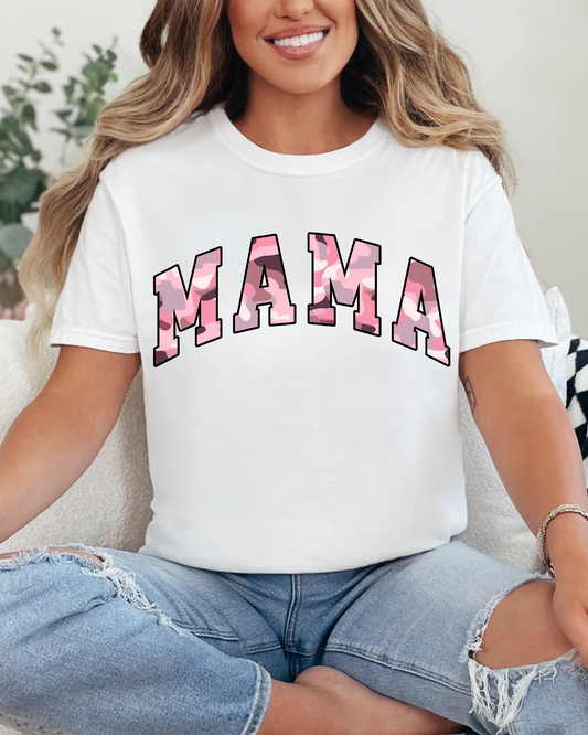 Woman wearing a white t-shirt with 'MAMA' printed in pink, sitting on a couch.