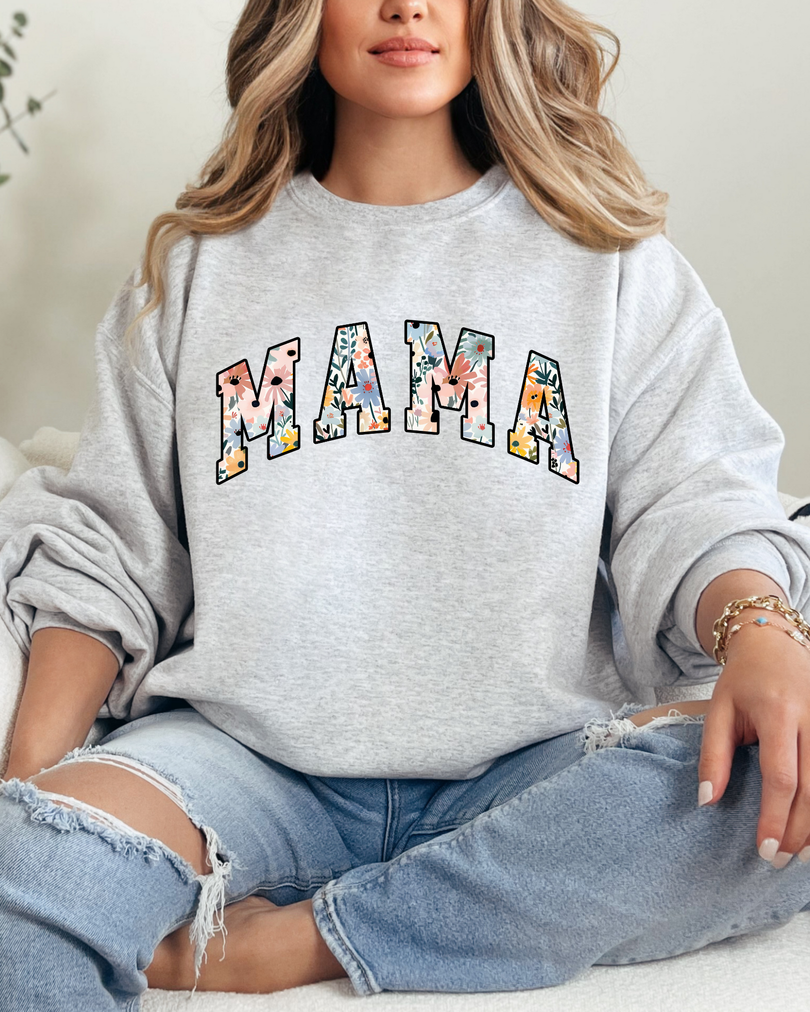 Person wearing a gray sweatshirt with 'MAMA' printed on it, sitting on a couch.