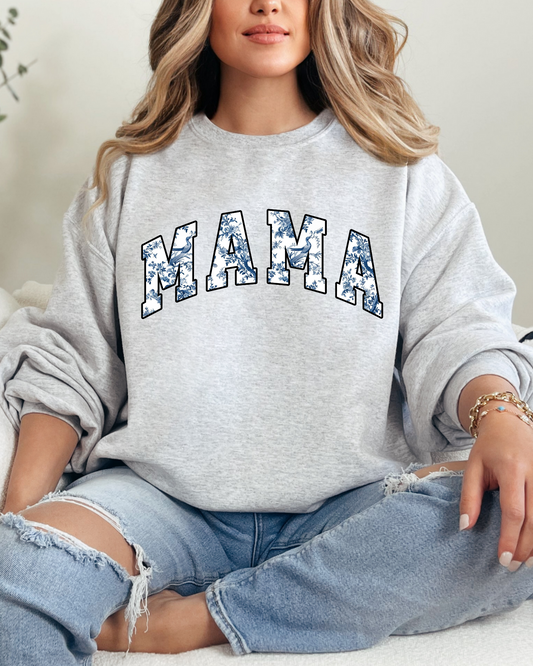 Woman wearing a gray sweatshirt with 'MAMA' printed on it, sitting on a couch.