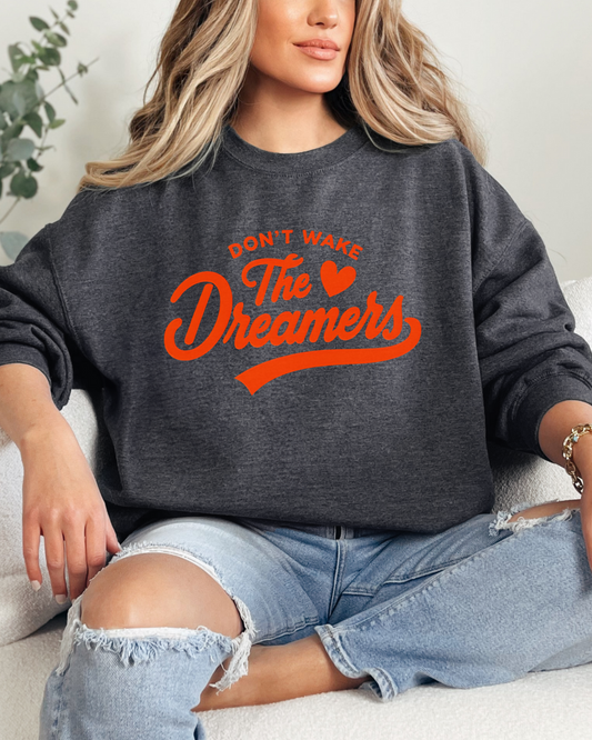 Person wearing a dark gray sweatshirt with red text sitting on a white couch.