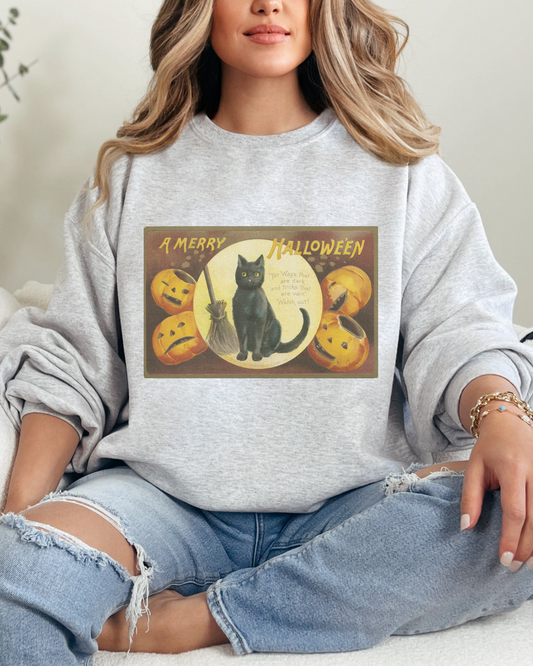 Person wearing a gray sweatshirt with a Halloween design, sitting on a couch.