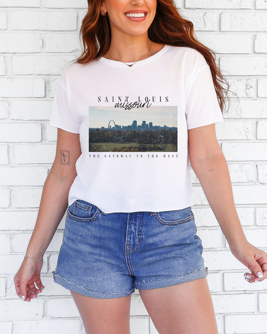 Person wearing a white t-shirt with a graphic design in front of a white brick wall