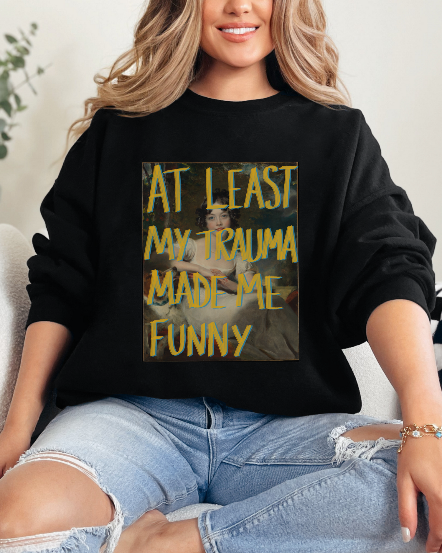 Person wearing a black sweatshirt with a graphic design and text, sitting on a couch.