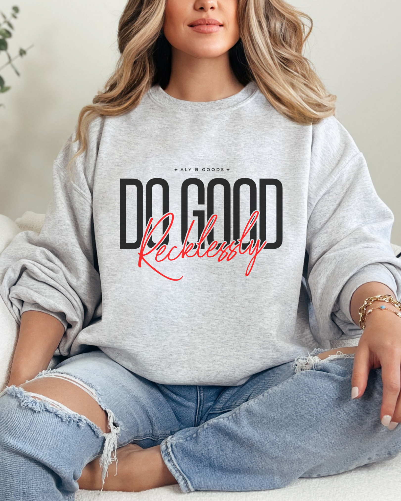 Person wearing a gray sweatshirt with text, sitting on a couch.