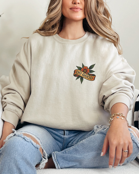 Woman wearing a beige sweatshirt with a logo sitting on a couch.